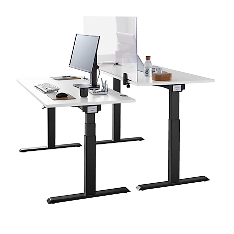 Two height-adjustable desks in L-shape, white with black frame. On one monitor, paper, mouse, pen holder, on it a partition.