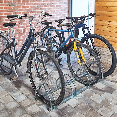 Fietsen in een fietsenrek, voor een bakstenen muur.