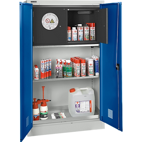 Offener Stahlschrank mit Chemikalien, Spraydosen und Kanistern. Der Schrank hat blaue Türen, innen graue Farbe und ein Warnschild.