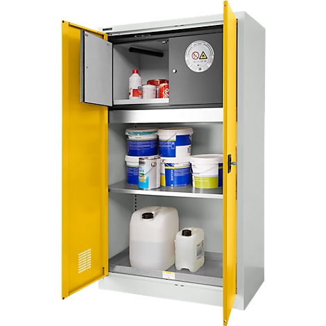 Ein offener, gelb-grauer Sicherheits-Schrank, gefüllt mit Flüssigkeiten, Farbeimern und Kanistern. Oben ein kleiner Tresor mit Warnhinweis.