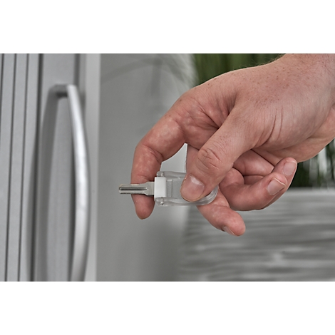 A hand holding a key in front of a door. The key is in a transparent case.