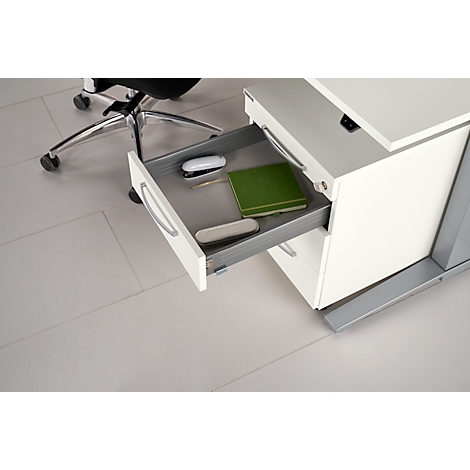 White desk with open drawer. Inside: stapler, notebook, pen, and case. Gray floor.