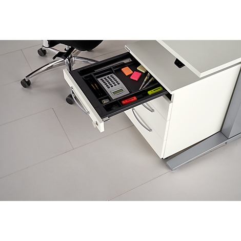 Office desk with open drawer; calculator, markers, pens. Next to it, office chair.