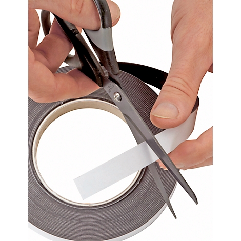 Hands cutting a piece of tape with scissors from a roll.