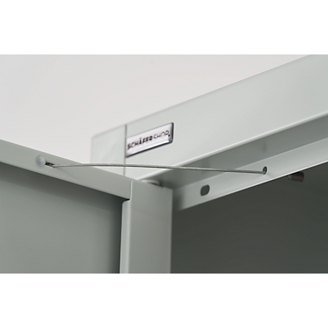 Close-up of a corner section of a cabinet, light grey. A wire is stretched.