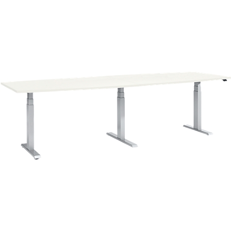 White, long desk with three height-adjustable, silver legs.