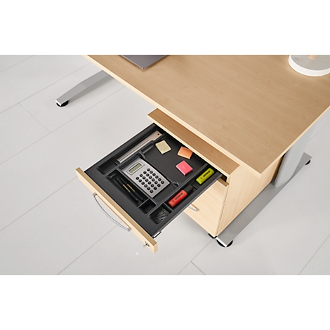 Desk with drawer pulled out. The drawer contains a calculator, pens, sticky notes and highlighters.