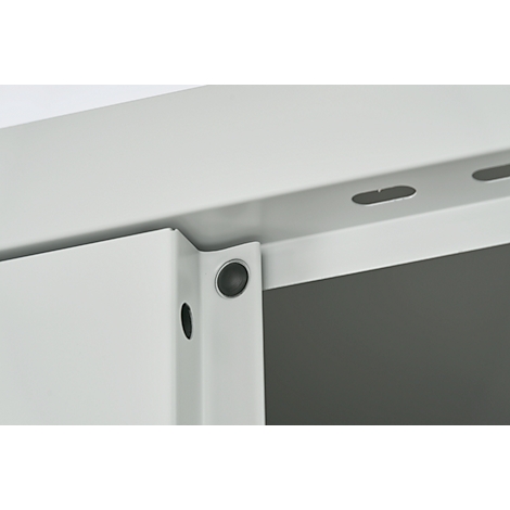 Close-up van een deel van een witte metalen plank. Het detail toont een hoek met een zwarte knop en schroefgaten.
