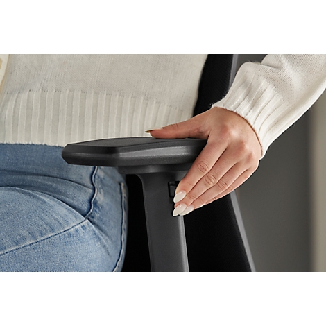 Close-up of a hand on an armrest, pressing a button. The person wears a white sweater and jeans.