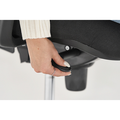 A woman adjusts the height of a black office chair, pressing a lever beneath the seat.