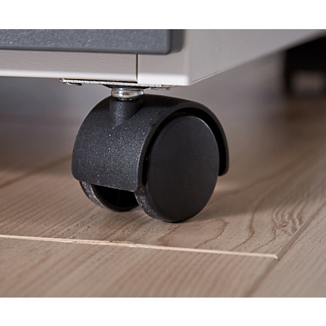 Close-up of a black furniture caster. On light wooden flooring. At the top edge, a part of a cabinet.