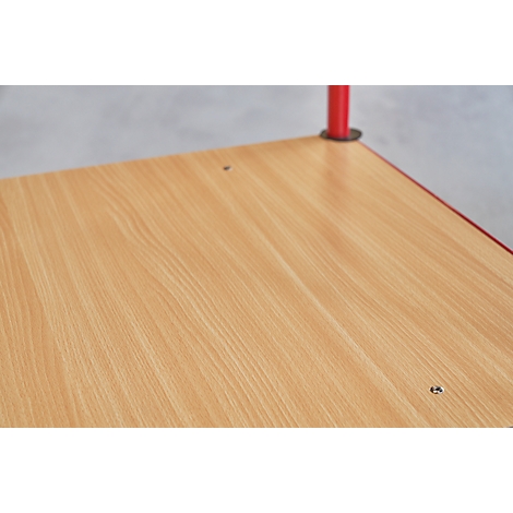 Close-up van een tafelblad met houtnerf. Rode poot van een tafel rechtsboven.