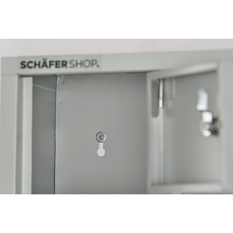 Grey cabinet with open door and lock. The lettering "SCHÄFER SHOP" can be seen in the background.