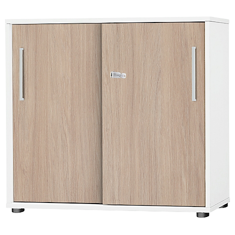 Kleiner Schrank mit zwei Schiebetüren. Türen aus hellem Holz mit silberfarbenen Griffen und weißem Korpus.