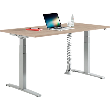 Höhenverstellbarer Schreibtisch mit Holzplatte, Laptop, Notizbuch und Spiralkabelkanal vor weißem Hintergrund.