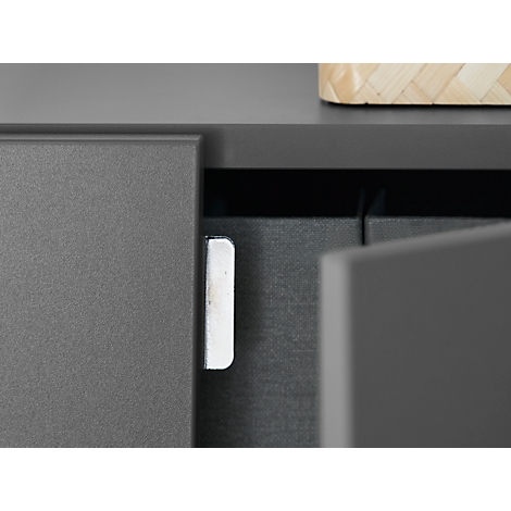 Close-up of a grey furniture edge with a silver hinge. A door is half open.