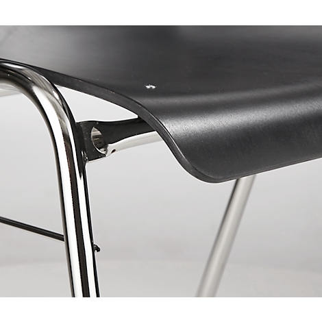 Close-up of a black chair with silver legs and a curved seat. The smooth surface reflects the light.