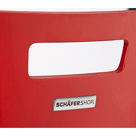 Close-up of a red chair. A rectangular hole and a small sign that says SCHÄFERSHOP.