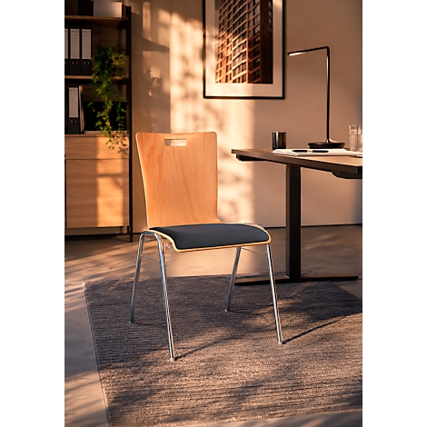 Ein moderner Holzstuhl mit dunkelgrauem Sitzpolster steht in einem warm beleuchteten Heimbüro.