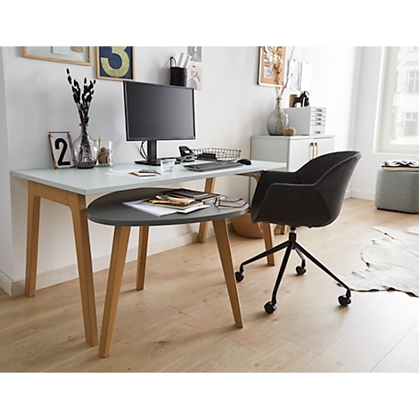 Light-design desk with chair, monitor and accessories. The desk has a shelf and light wooden legs. On the desk is a monitor, keyboard and paper.