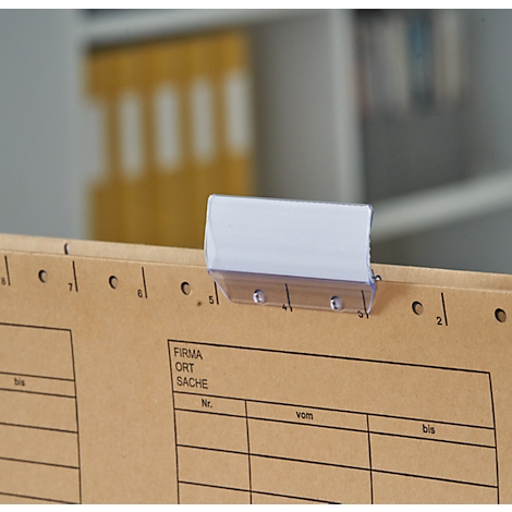 Close-up of a brown file with lettering. A white stick-on label holder is attached.