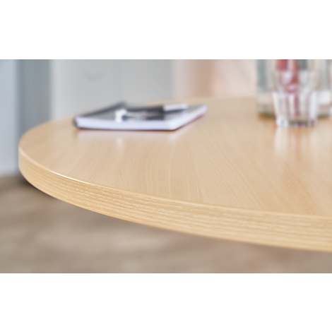 Light brown, round table with notebook and pen. Glasses in the background.