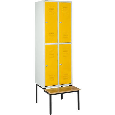 Un casillero blanco y amarillo con cuatro puertas, con un pequeño banco delante.