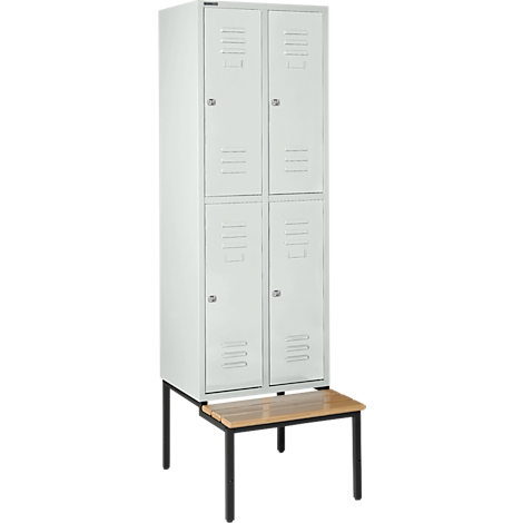 Taquilla gris con cuatro puertas y ranuras de ventilación, de pie sobre un banco.