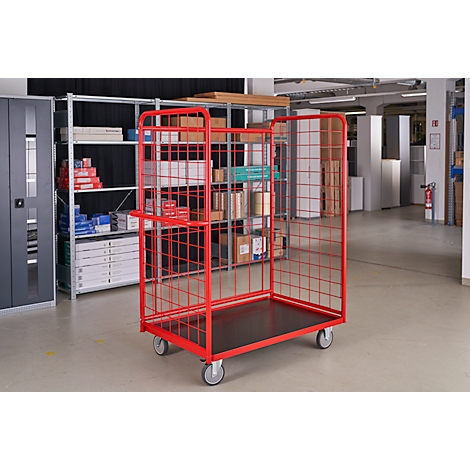Red transport cart with grid, on wheels. In a warehouse, filled with goods.