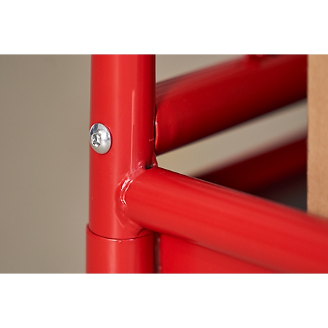 Close-up of a red metal construction, fastened with a screw. The background is light beige.