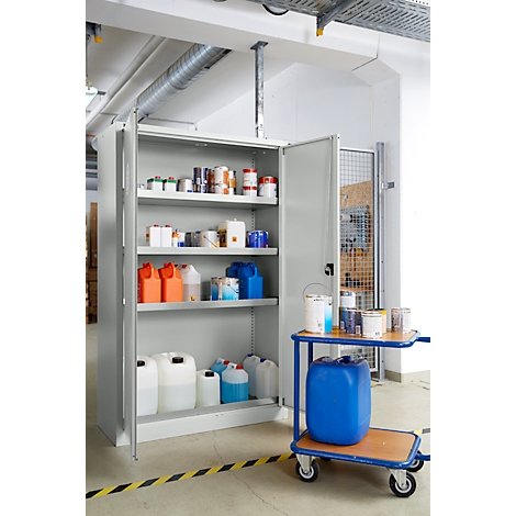 Grauer Schrank mit geöffneten Türen, gefüllt mit Farbbehältern und Chemikalien. Auf einem Wagen steht eine blaue Tonne.