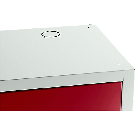 Ecke eines weißen Schranks mit roter Tür und Lüftungsloch. Minimalistisches Design.