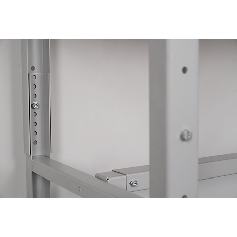 Gray metal construction with screws and boreholes. The construction is depicted in front of a light wall.