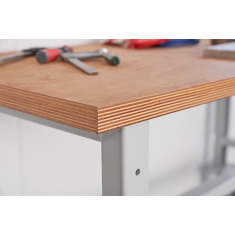 Close-up of a workbench, showing layered wooden panels. Tools are lying in the background.