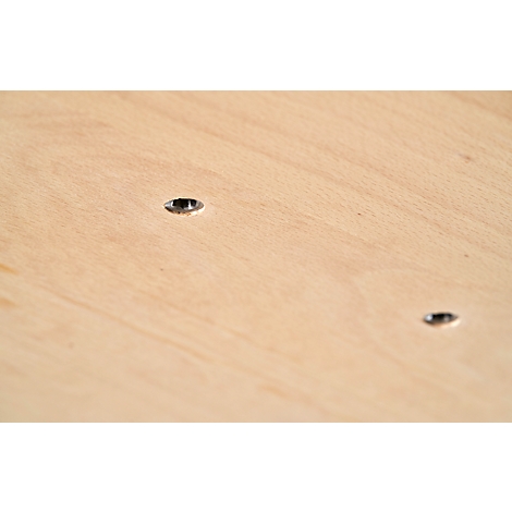 Close-up of a wooden board with two round, dark holes.