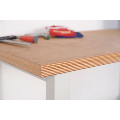Close-up of a wooden table edge, with tools in the background. Geometric lines. The table edge is made of veneer.