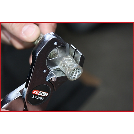 Person hält Werkzeug, schneidet transparenten Schlauch. KS TOOLS, 222.2060 ist auf dem Werkzeug zu sehen.