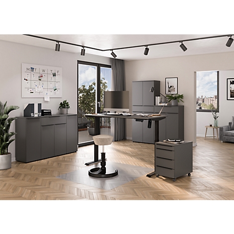 Ein modernes Büro mit dunklen Möbeln. Ein Schreibtisch steht vor einer Balkontür, ein Drehhocker davor. Eine Pinnwand und Pflanzen schmücken den Raum.