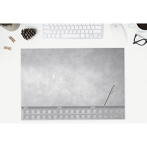 Grauer Schreibtischunterlage mit Jahresübersicht, Stift, Tastatur, Maus, Brille, Kaffeetasse, Deko und Klammern. Von oben fotografiert.