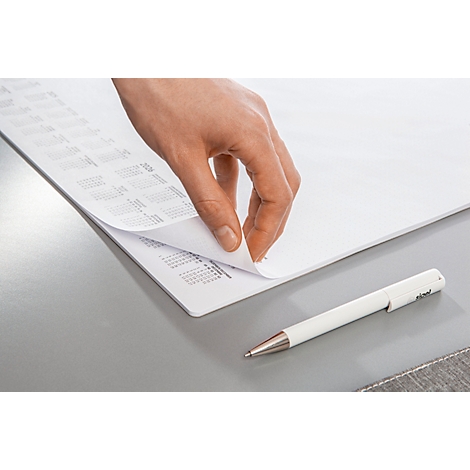 Hand blättert Seite von Kalender auf grauem Tisch um. Daneben liegt ein weisser Stift.