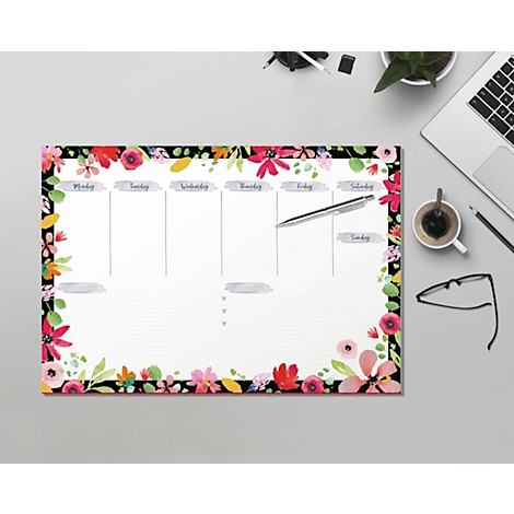 Ein floraler Wochenplaner liegt auf einem Schreibtisch, umgeben von Stiften und Laptop.
