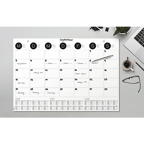 Ein weisser Wandkalender für September, mit Terminen notiert. Daneben liegen eine Brille, ein Stift, eine Kaffeetasse und ein Laptop.