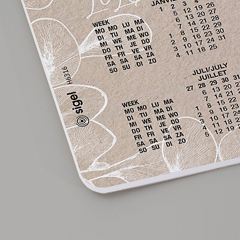 Beige Notizblock mit Monatskalender-Aufdruck und Blumendekor. Links unten das Sigel-Logo.