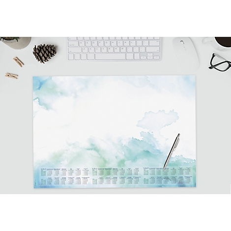 Schreibtischunterlage mit blau-grünen Aquarellflecken, darunter Jahreskalender. Stift liegt bereit.