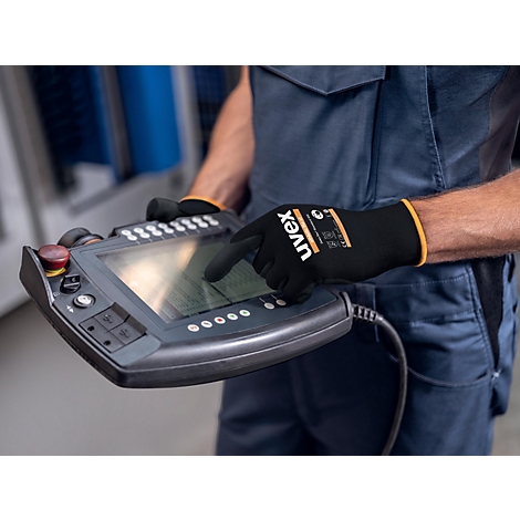 Person in blauer Arbeitskleidung bedient Steuergerät. Schwarze Handschuhe mit Uvex-Logo, gelbe Details.