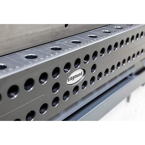 Detailaufnahme einer schwarzen Siegmund-Schweißtischkomponente mit kreisförmigen Löchern und Skalen. Das Logo 'Siegmund' ist prominent.