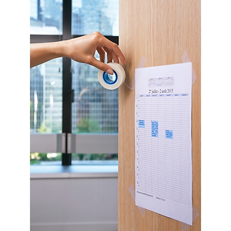 Hand plakt een notitie aan houten muur met plakband. Raam op de achtergrond.