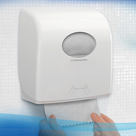 Weisser Papierhandtuchspender an weisser Wand. Hände ziehen Papier heraus. Markierung von Kimberly-Clark.