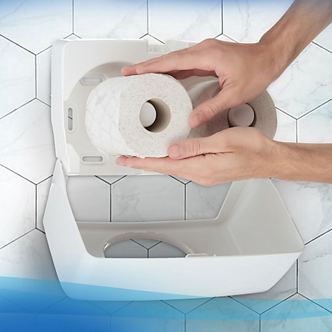 Hände halten eine neue Toilettenpapierrolle in einem weißen Spender vor weißem Fliesen Hintergrund.