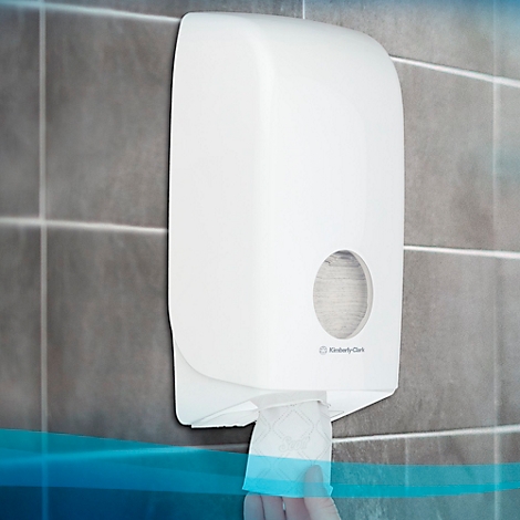 Weißer Papierhandtuchspender an grauer Wand. Ein Blatt Papier wird entnommen. Der Schriftzug "Kimberly Clark" ist sichtbar.
